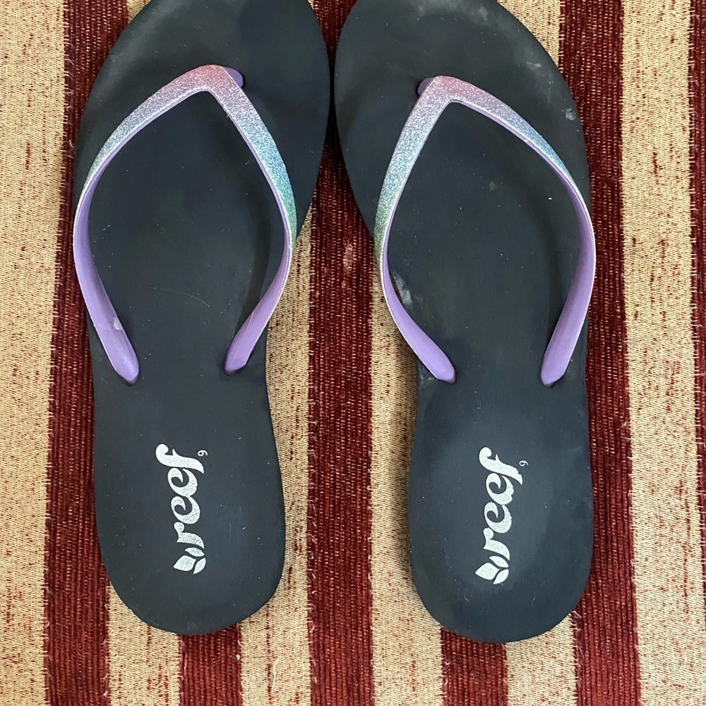 Reef flip flops, black bottoms with purple iridescent straps. Size 8.5